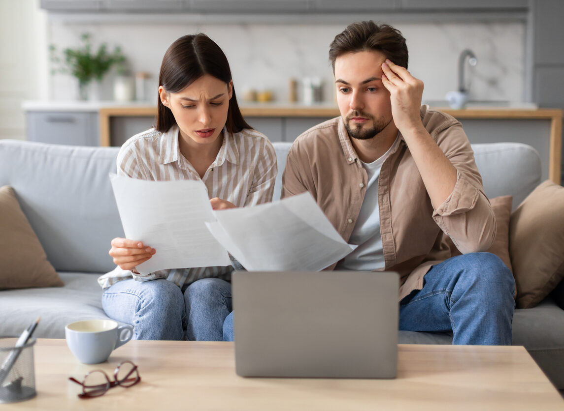Anxious couple with laptop and papers on the couch